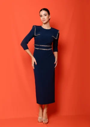 Mujer con vestido midi azul marino ajustado, con detalles de flecos pasamanería en hombros y cintura. Vestido elegante ideal para eventos y ocasiones especiales.